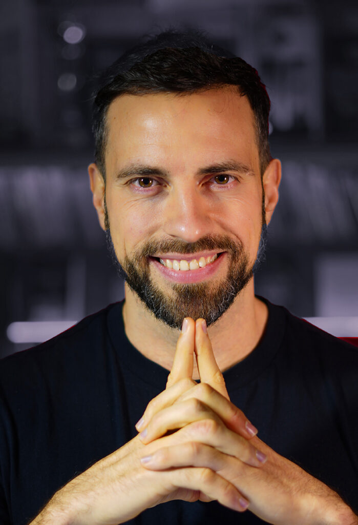 Cristian Torres sonriendo con las manos juntas sobre un fondo oscuro